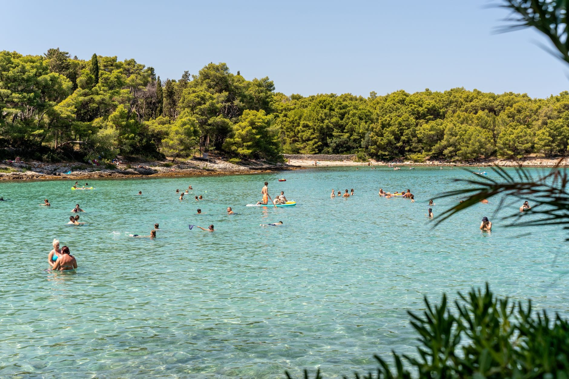 Plaże Chorwacji dla rodzin z dziećmi: najciekawsze miejsca nad Adriatykiem Rodziny kąpiące się w przejrzystym morzu na plaży w Supetar w Chorwacji
